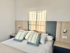 a bedroom with a bed with white and blue pillows at Santo Rostro Beach Apartments in Chipiona