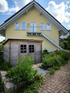 a yellow house with a porch and a balcony at Dachgeschosswohnung im Grünen in Waldshut-Tiengen +4 photos
