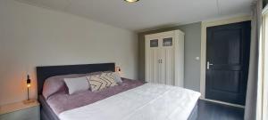 una camera da letto con un grande letto bianco con due cuscini di Stijlvol chalet Zeeland - Sauna & omheinde tuin VP082 a heinkenszand Altre 41 foto