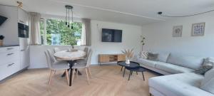 un soggiorno con un tavolo e un divano di Stijlvol chalet Zeeland - Sauna & omheinde tuin VP082 a heinkenszand