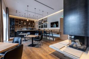 a bar with a fireplace and tables and chairs at Seehotel Bellevue by keyone in Zell am See