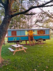 a blue and orange train car parked next to a picnic table at Roulotte de charme in Villers-sur-Authie