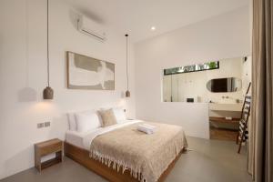 a white bedroom with a bed and a kitchen at Balear Villa in Kuta Lombok