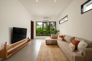 a living room with a couch and a flat screen tv at Balear Villa in Kuta Lombok