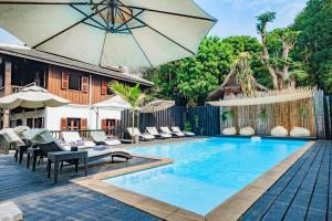 una piscina al aire libre con sillas y sombrilla en Sanctuary Hotel Luang Prabang, en Luang Prabang