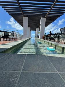 a swimming pool on a building with tables and chairs at SUITE PREMIUM VISTA MAr in João Pessoa