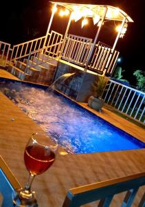 a glass of wine sitting on a table next to a swimming pool at Villa Victoria Campestre in Rivera