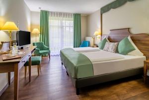 a hotel room with a large bed and a desk at Schloßhotel Althörnitz in Hörnitz