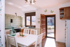 una cucina con tavolo e sedie bianchi e frigorifero di O Lar do Bispo by CABANA Rentals a Arbo