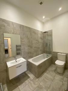 a bathroom with a tub and a toilet and a sink at Stunning 1 Bed Apartment - Perfect for Couples or Solo Stays in Tadworth