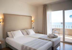 two beds in a hotel room with a view of the ocean at FAY Victoria Beach in Rincón de la Victoria