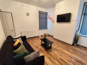 a living room with a couch and a flat screen tv at Double-Bedroom in the Heart of Harpurhey Manchester A3 Perfect for Short Stays in Manchester