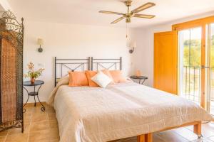 a bedroom with a bed with orange pillows and a ceiling fan at Casa de las Cañas by Rosas Cantares in Pizarra