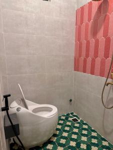 a bathroom with a toilet with a green floor at Thalia Home Măng Đen in Kon Plong