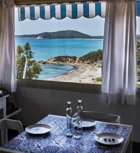 a table with a view of a beach from a window at Elegant Seaview Home w AC e Free Private Park in Simius