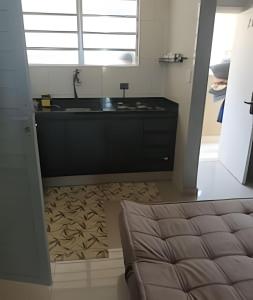 a kitchen with a sink and a couch in a room at Studio à Beira-mar - Santos in Santos