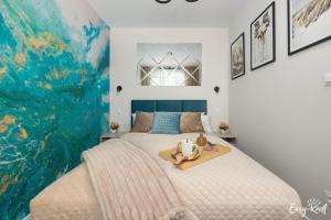 a bedroom with a large bed with a painting on the wall at De-Lux M - Easy - Rent Apartments in Niechorze