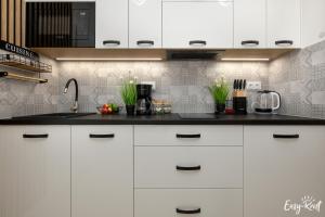a kitchen with white cabinets and a black counter top at De-Lux M - Easy - Rent Apartments in Niechorze