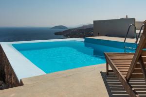 a blue swimming pool with a bench and the ocean at villa Agnantia, Leros in Lakkíon