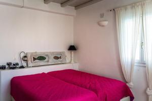 a red bed in a white room with a window at villa Agnantia, Leros in Lakkíon +22 photos