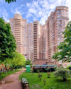 a park with benches in front of a large building at Golosievo residence 60m2 in Kyiv