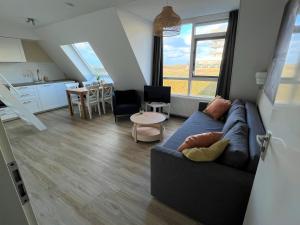 a living room with a blue couch and a kitchen at Moana3 Seaview in Egmond aan Zee