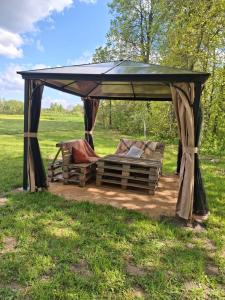 a gazebo with two chairs under it in a field at Camping "Sīvezers" in Auleja