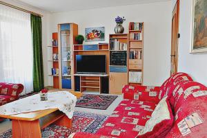 Una sala de estar con un sofá rojo y un televisor. en Landhaus Seiler, en Freudenstadt