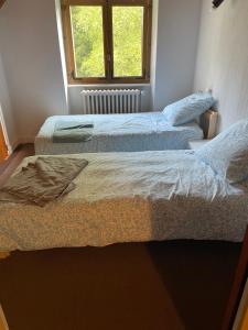 two beds in a room with a window at Grande maison familiale in Tortebesse