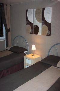 1 dormitorio con 2 camas y mesa con lámpara en Melrose Guest House, en Whitley Bay