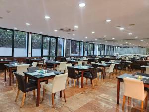 a dining room with tables and chairs and windows at Lloret Vibe Affiliated by FERGUS in Lloret de Mar