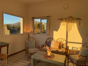 een woonkamer met stoelen en een tafel en ramen bij Casa Agua Marfil in Capilla del Monte