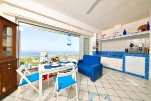 a kitchen with a table and blue chairs and a window at Villa Bianca Un angolo di paradiso in Ischia