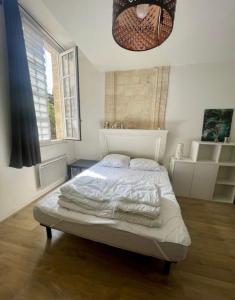a bedroom with a bed with white sheets and a window at Little Saint James au coeur historique de Bordeaux in Bordeaux