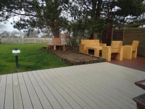 a wooden deck with a picnic table and benches at Ferienhaus Achtein in Westoverledingen