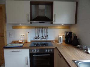 a kitchen with white cabinets and a black stove top oven at Ferienhaus Achtein in Westoverledingen