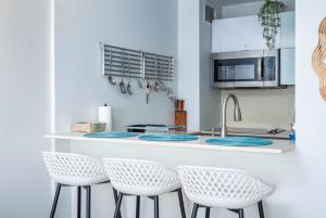 - une cuisine avec des comptoirs et des tabourets blancs dans l'établissement Sea La Vie Beachfront Condo With Dreaming View, à Luquillo