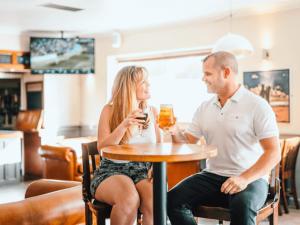 a man and a woman sitting at a table with drinks at Golden Coast Leisure Park - Ocean Tide Villa 3 T in Woolacombe