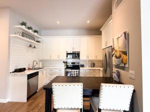 ナイアガラ・オン・ザ・レイクにあるContemporary West Loft in Historic Niagaraの白いキャビネットとテーブルと椅子のあるキッチン +19枚の写真