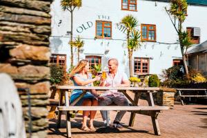 Ein Mann und eine Frau sitzen mit einem Glas Wein an einem Picknicktisch in der Unterkunft Golden Coast Leisure Park - Ocean Tide Villa I in Woolacombe