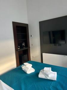 Dos toallas en una cama azul con un televisor. en Luxury Room, en Bari 2 fotos más