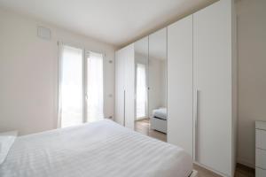 una camera da letto bianca con un letto e uno specchio di Parco Comfort Suite Battaglia Appartamenti a Milano