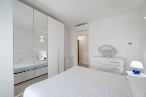 una camera da letto bianca con un letto e uno specchio di Parco Comfort Suite Battaglia Appartamenti a Milano
