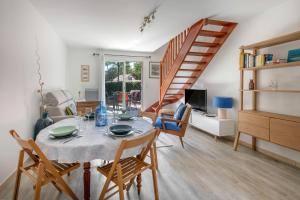 ein Esszimmer mit Tisch und Stühlen und einer Treppe in der Unterkunft Maison pour 4 avec terrasse - proche du centre in Saint-Brévin-lʼOcéan
