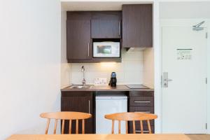 a small kitchen with wooden cabinets and two stools at Apartamentos Caprice Playa de Alcudia in Port d'Alcudia