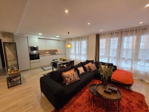 a living room with a black couch and a kitchen at Avilés Luce B - 3 habitaciones - 2 baños - VUT-7461-AS in Avilés