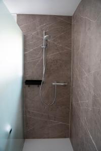 a shower in a bathroom with a stone wall at Berghaus Schäfer in Faschina +15 photos