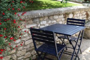 a black table and chair next to a stone wall at La Clé des Clos in Beynes