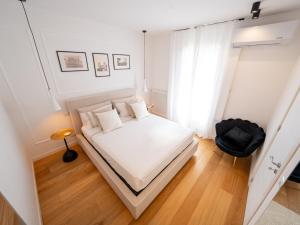a bedroom with a white bed and a black chair at Maison Odile in Cefalù