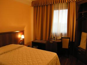 a hotel room with a bed and a desk and a window at Dado Hotel International in Parma